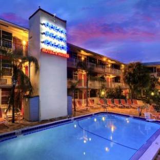 Hotel with illuminated sign, pool, and lounge chairs at dusk.
